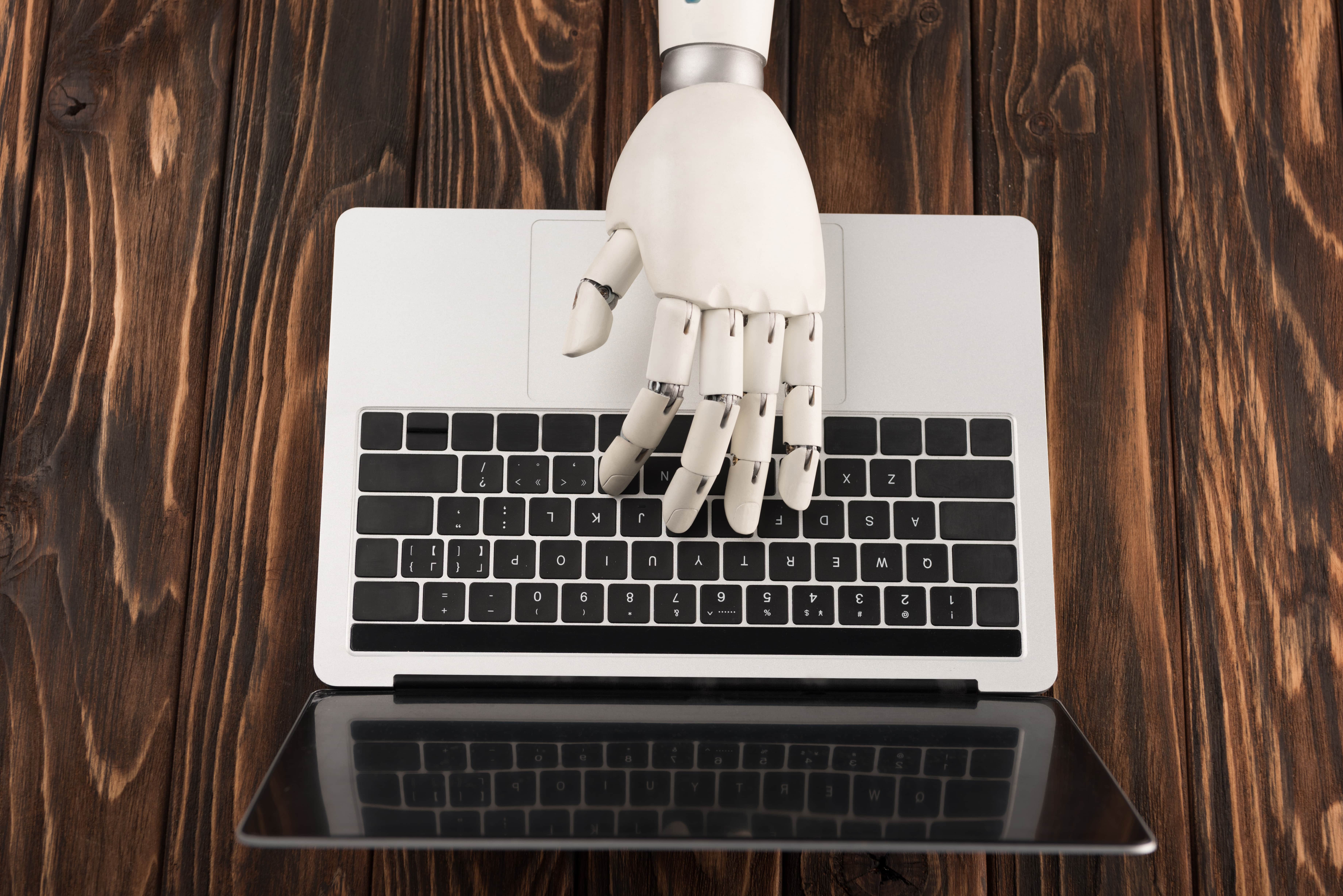 shot-of-robot-working-with-laptop-on-woode